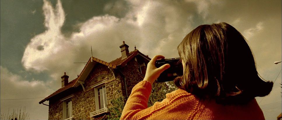 A woman photographing a house under a dramatic sky