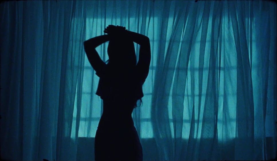 A woman in silhouette against a curtain